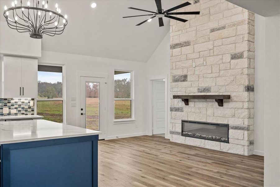 Kitchen featuring white cabinetry, a fireplace, a healthy amount of sunlight, and decorative light fixtures