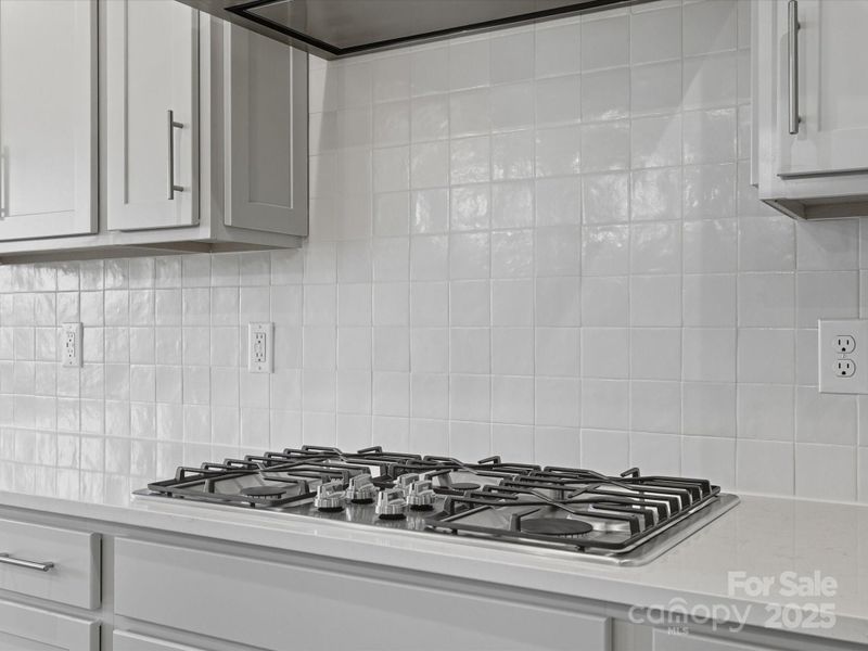 Gas cooktop and crisp white backsplash.