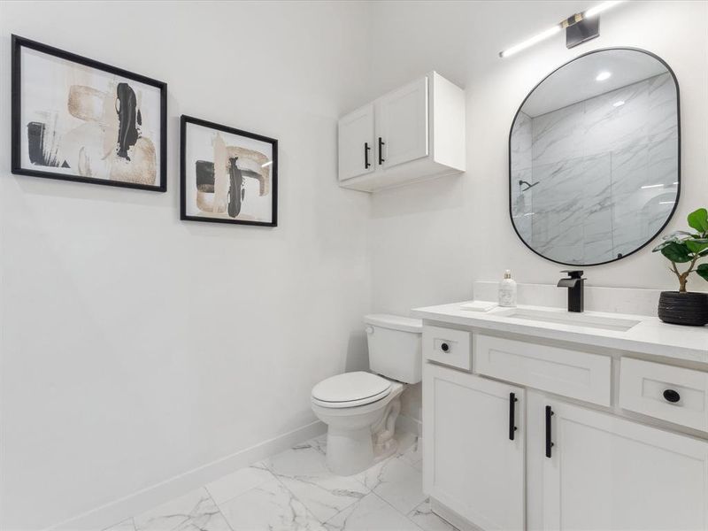 Full bath with a marble finish shower, baseboards, toilet, marble finish floor, and vanity