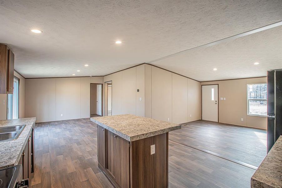 Kitchen featuring a textured ceiling, black fridge, a kitchen island, dark hardwood / wood-style flooring, and sink Kitchen featuring a textured ceiling, black fridge, a kitchen island, dark hardwood / wood-style flooring, and sink