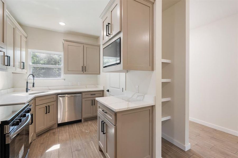 Modern kitchen featuring grey shaker cabinetry, white stone countertops, stainless steel appliances, and wood-finish flooring Modern kitchen featuring grey shaker cabinetry, white stone countertops, stainless steel appliances, and wood-finish flooring