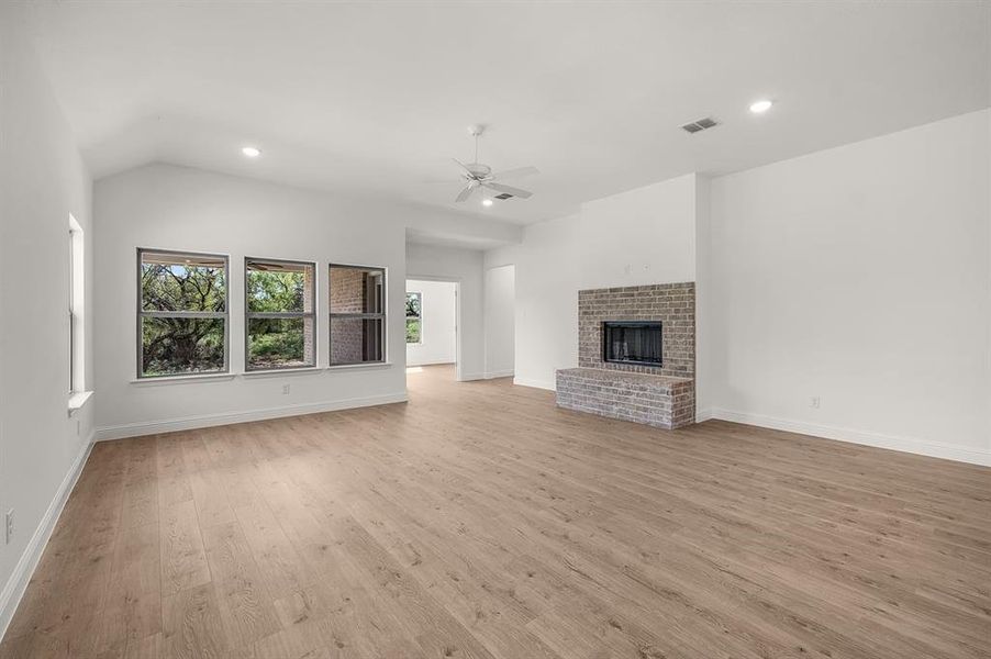 Unfurnished living room featuring recessed lighting, light floors, a fireplace, lofted ceiling, and ceiling fan