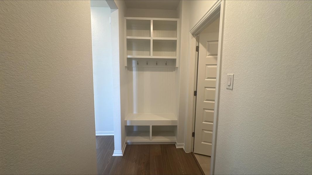 Mudroom with a textured wall and dark wood finished floors