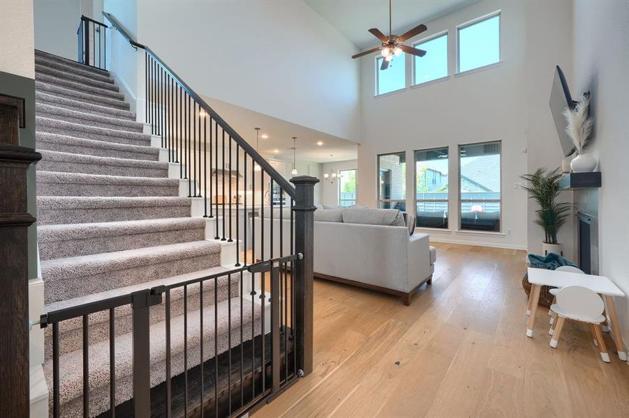 Living room featuring light hardwood / wood-style floors, ceiling fan, and a high ceiling