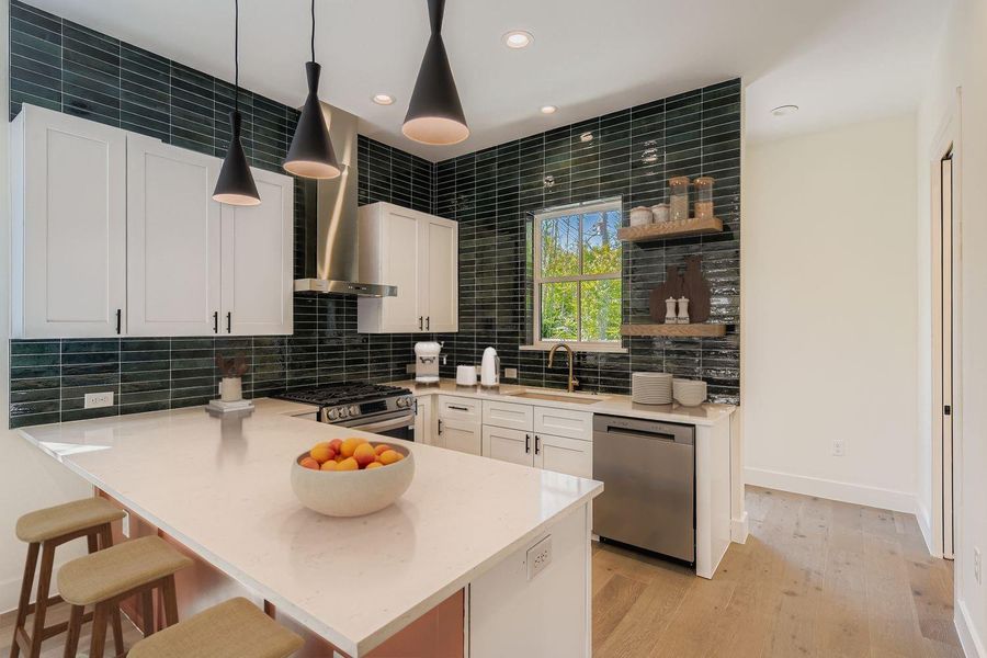 Kitchen with a kitchen breakfast bar, recessed lighting, decorative backsplash, a peninsula, and wall chimney exhaust hood Kitchen with a kitchen breakfast bar, recessed lighting, decorative backsplash, a peninsula, and wall chimney exhaust hood
