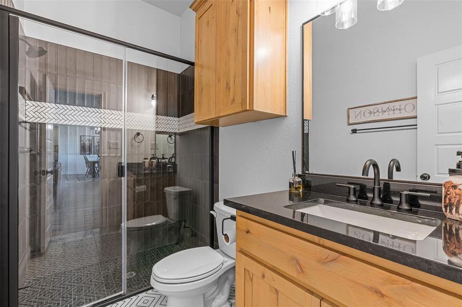 Bathroom with vanity, toilet, and a shower with shower door