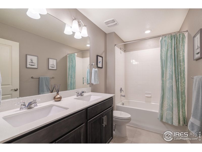 Shared upstairs bathroom with quartz countertops.