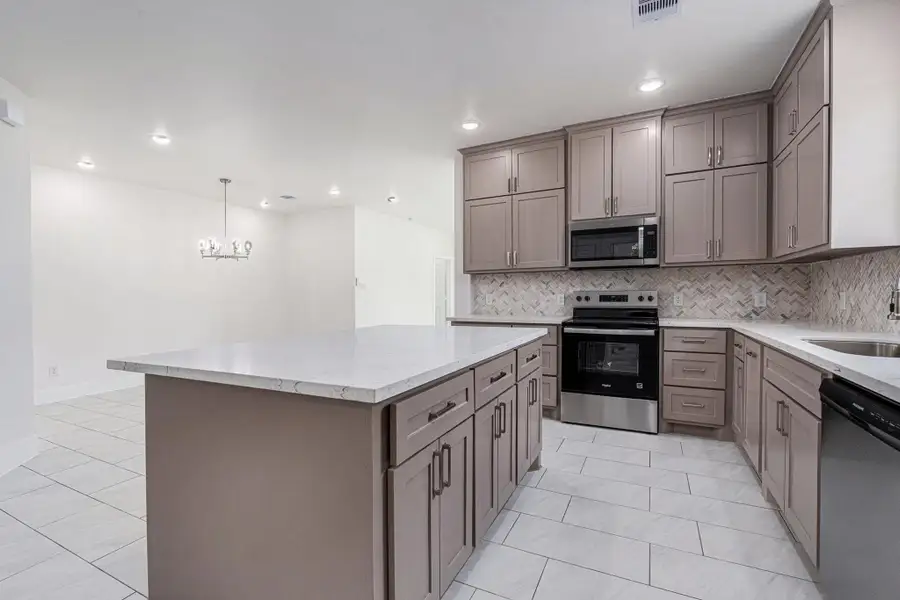 This photo showcases a modern kitchen with sleek cabinetry, stainless steel appliances, and a spacious island. The neutral color palette, combined with the stylish backsplash and tile flooring, creates a clean and inviting atmosphere. The open layout leads to a dining area with a contemporary chandelier. This photo showcases a modern kitchen with sleek cabinetry, stainless steel appliances, and a spacious island. The neutral color palette, combined with the stylish backsplash and tile flooring, creates a clean and inviting atmosphere. The open layout leads to a dining area with a contemporary chandelier.
