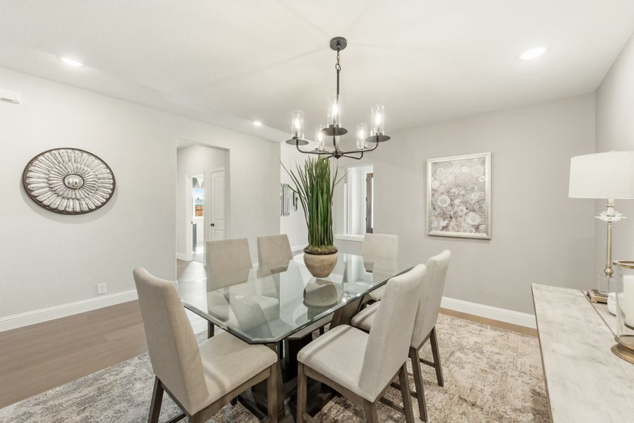 Dining room with glass-top table, six upholstered chairs, and a chandelier overhead
