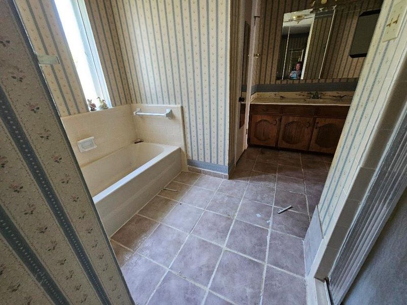 Full bath with wallpapered walls, a bath, vanity, and tile patterned flooring Full bath with wallpapered walls, a bath, vanity, and tile patterned flooring