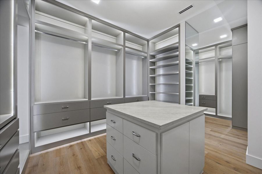 The oversized walk-in closet is designed like a high-end dressing room, complete with custom built-ins, extensive storage, and a center island.