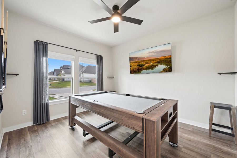 A spacious game room features rich wood-look flooring and ample natural light from twin windows. A spacious game room features rich wood-look flooring and ample natural light from twin windows.