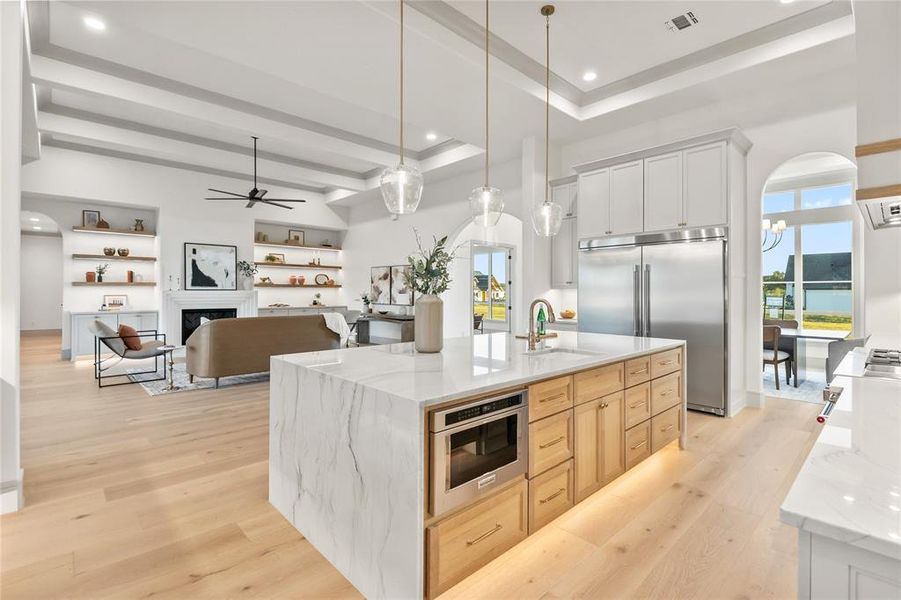 Two tone kitchen with arched walkways, light stone counters, open floor plan, a tray ceiling, and two tone color scheme Two tone kitchen with arched walkways, light stone counters, open floor plan, a tray ceiling, and two tone color scheme