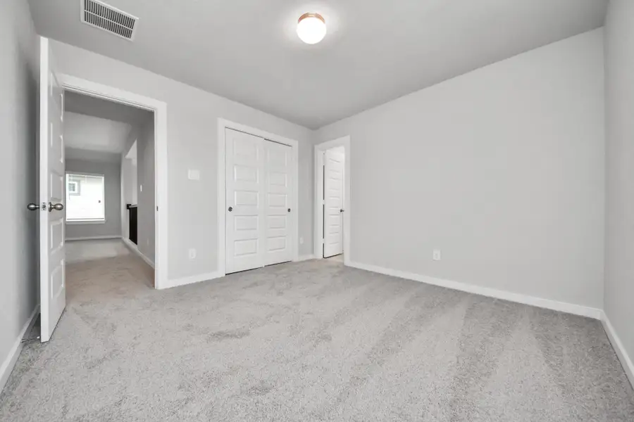 Secondary bedroom features plush carpeting, large windows that let in plenty of natural light, bright paint, and spacious closets. Sample photo of completed home with similar floor plan. Actual colors and selections may vary.