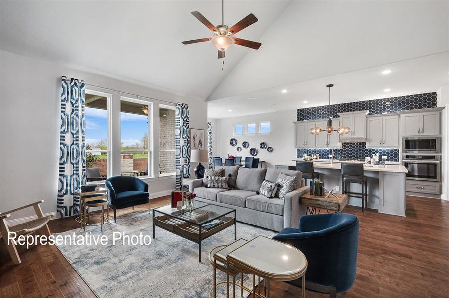 Living room featuring dark hardwood / wood-style floors, high vaulted ceiling, and ceiling fan with notable chandelier