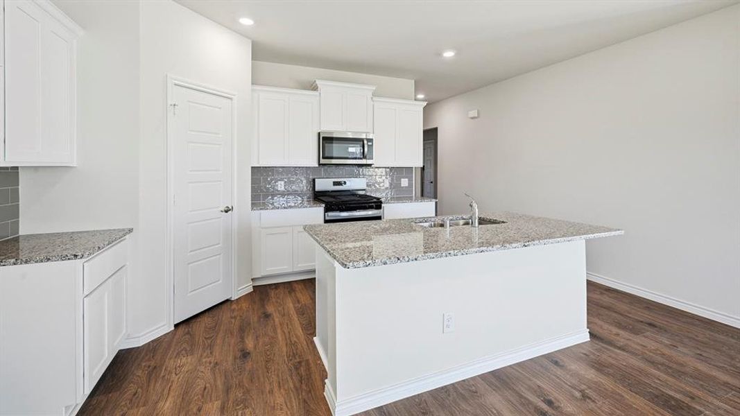 Kitchen featuring stainless steel appliances, light stone countertops, decorative backsplash, a center island with sink, and recessed lighting Kitchen featuring stainless steel appliances, light stone countertops, decorative backsplash, a center island with sink, and recessed lighting