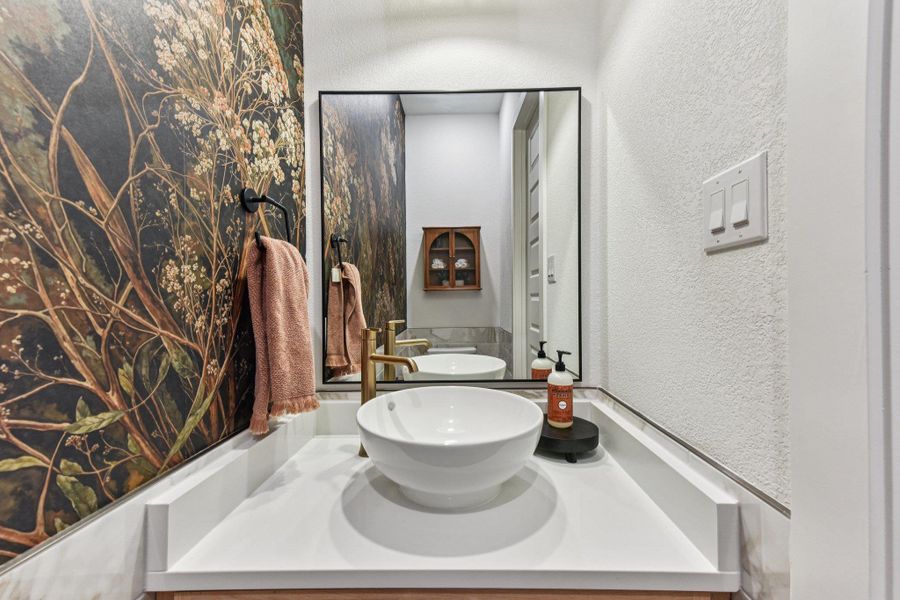 A modern vessel sink sits atop a clean vanity, paired with elegant brass hardware.