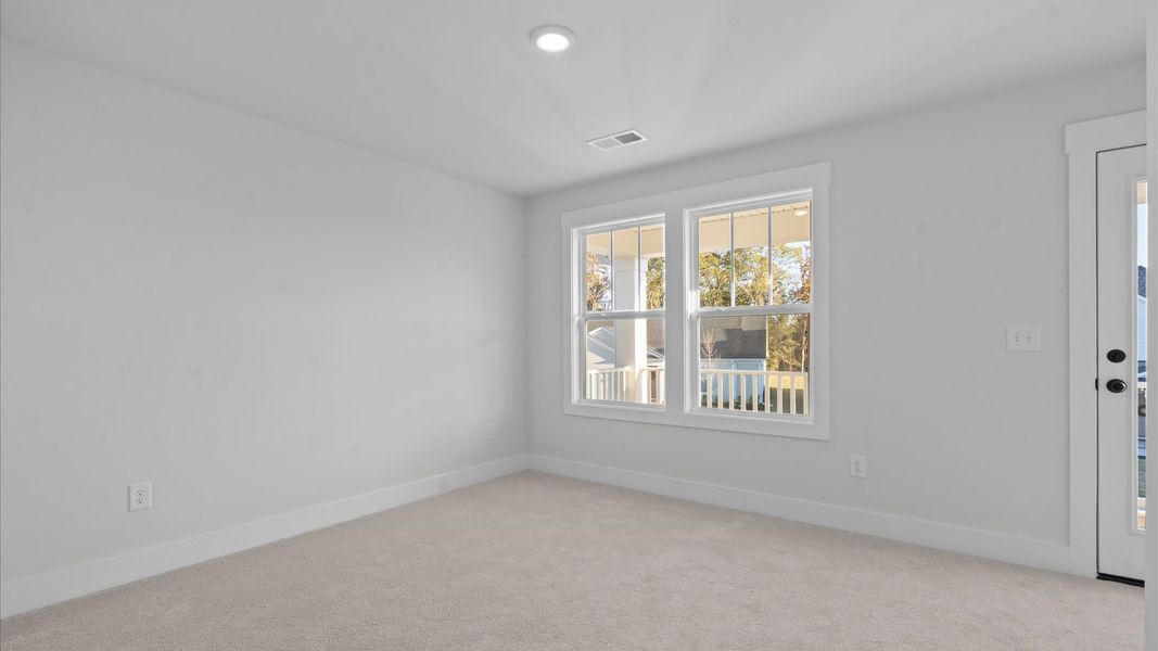 Tasteful bedroom with plush carpet, a walk-in closet, and large windows for abundant natural light