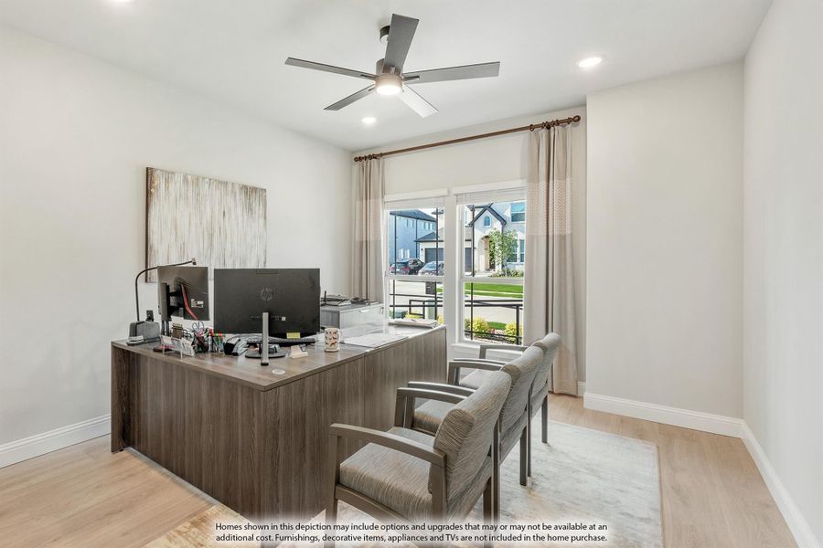 Home office with wood desk, dual monitors, two guest chairs, ceiling fan, and large window with neighborhood view Home office with wood desk, dual monitors, two guest chairs, ceiling fan, and large window with neighborhood view