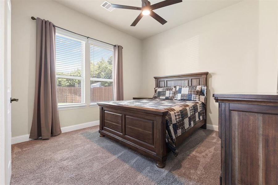 Carpeted room featuring a ceiling fan with integrated lighting, two double-hung windows with blinds, and neutral wall paint Carpeted room featuring a ceiling fan with integrated lighting, two double-hung windows with blinds, and neutral wall paint