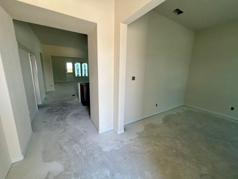 Hallway featuring unfinished concrete flooring and baseboards