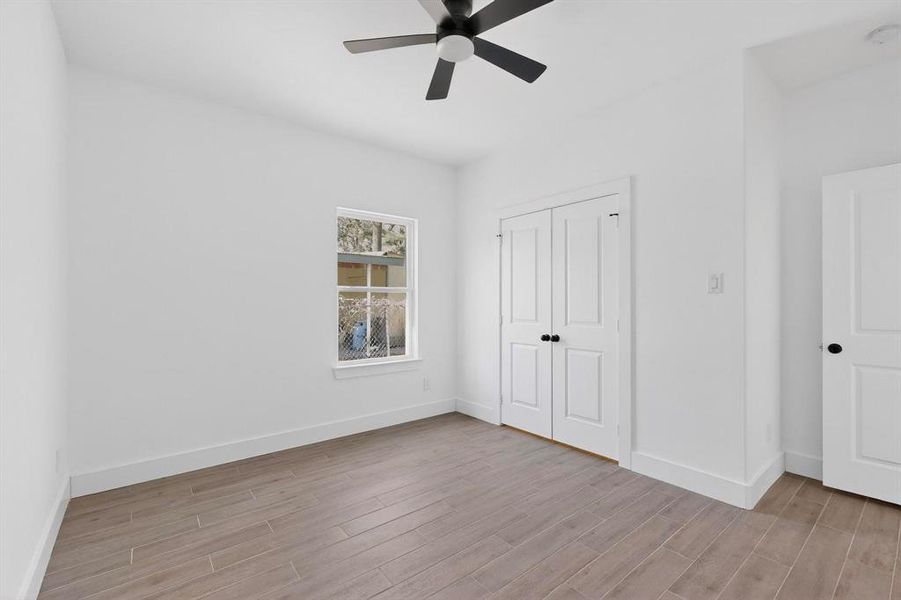 Unfurnished bedroom featuring light wood-type flooring, a closet, and ceiling fan