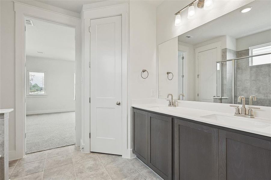 Bathroom with tile patterned floors, a shower with shower door, and vanity