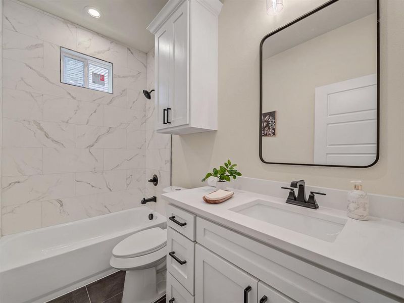 Full bathroom with toilet, tiled shower / bath combo, vanity, and tile patterned floors