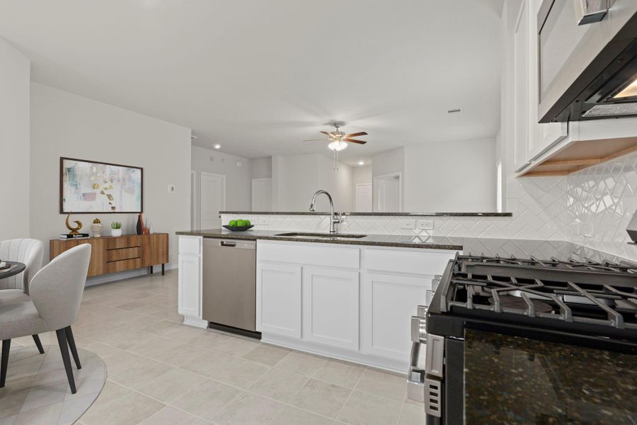 Another perspective of the virtually staged kitchen showcases sleek cabinetry, gas range, and modern finishes. The open connection to the family area keeps everyone connected during mealtime or entertaining.
