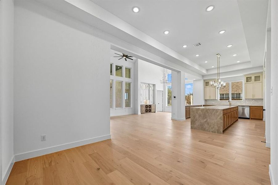 Kitchen featuring open floor plan, a chandelier, a kitchen island, tasteful backsplash, and light wood-style flooring Kitchen featuring open floor plan, a chandelier, a kitchen island, tasteful backsplash, and light wood-style flooring