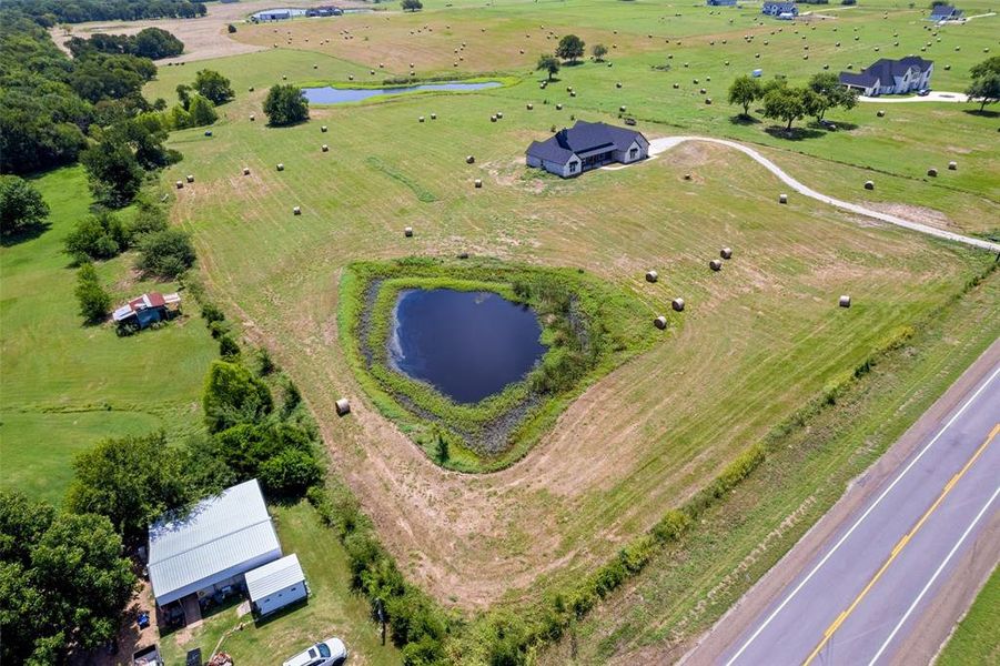 Expansive rural property featuring a private pond, open fields, and a modern single-story residence