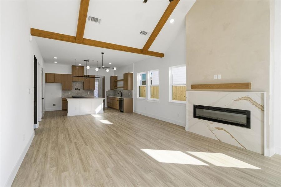 Unfurnished living room with recessed lighting, light wood-style floors, vaulted ceiling, and a glass covered fireplace