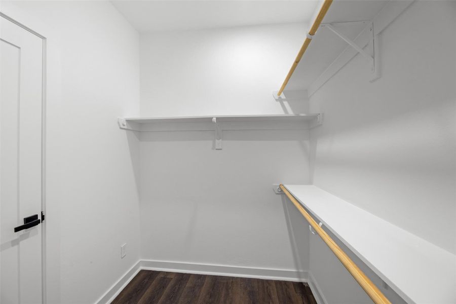 Huge walk-in closet with dark wood flooring. It features ample shelving and hanging space for storage. Huge walk-in closet with dark wood flooring. It features ample shelving and hanging space for storage.