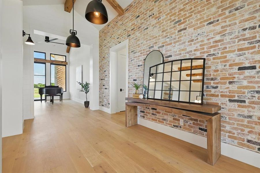 Corridor with high vaulted ceiling, wood finished floors, brick wall, and beamed ceiling Corridor with high vaulted ceiling, wood finished floors, brick wall, and beamed ceiling