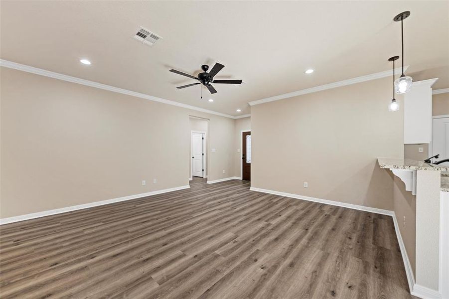 Unfurnished living room featuring a ceiling fan, recessed lighting, wood finished floors, and ornamental molding