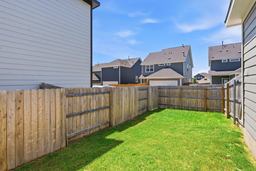 A well-maintained wooden fence encloses a private yard with lush green grass, offering a secluded outdoor retreat. A well-maintained wooden fence encloses a private yard with lush green grass, offering a secluded outdoor retreat.