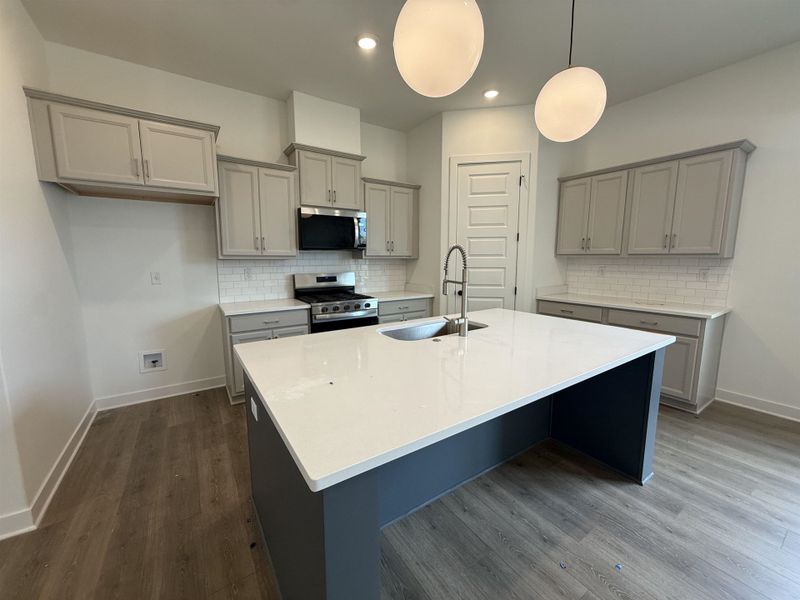Kitchen featuring a central island with a white countertop and deep gray base, complemented by light gray cabinetry