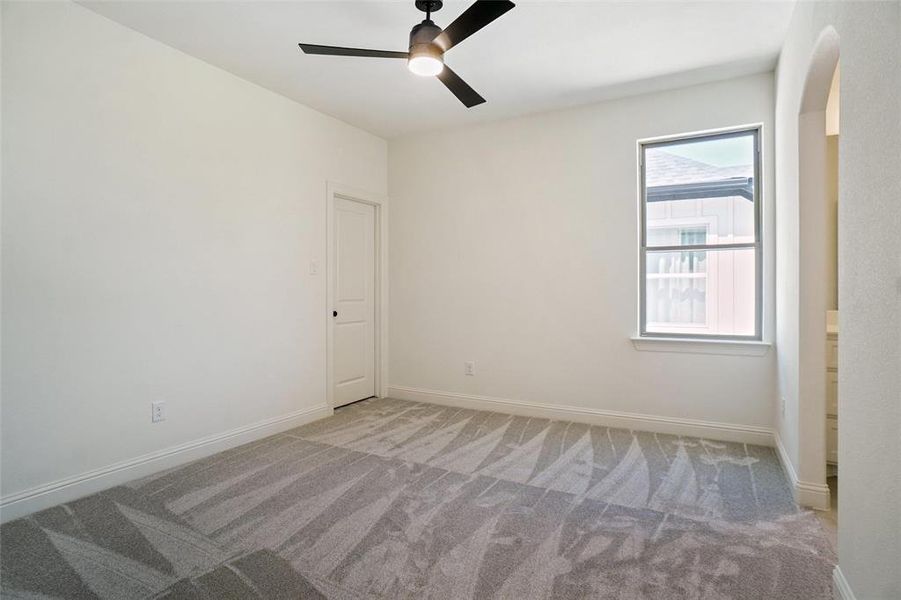 Empty room with ceiling fan, carpet flooring, and arched walkways Empty room with ceiling fan, carpet flooring, and arched walkways