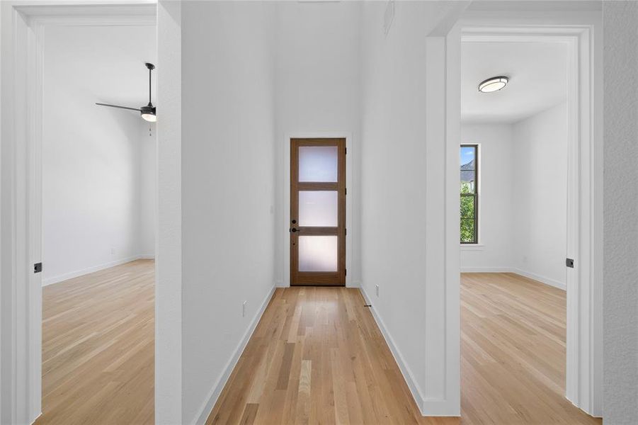 Entryway featuring wood-finish flooring, a contemporary door with frosted glass panels, and bright white walls