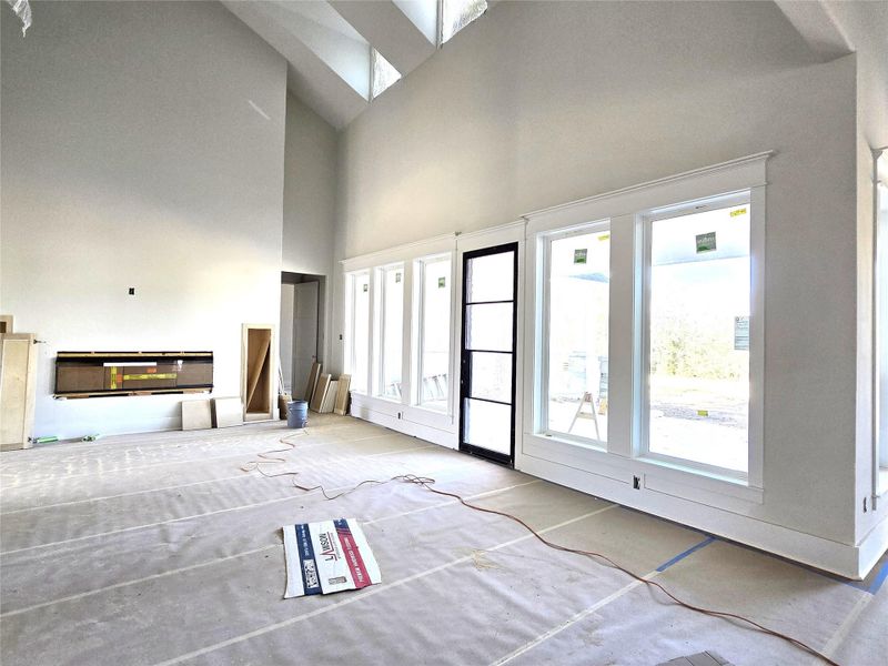 Partial view of the iving area with fireplace and covered patio through the windows. Note the high ceilings and design.