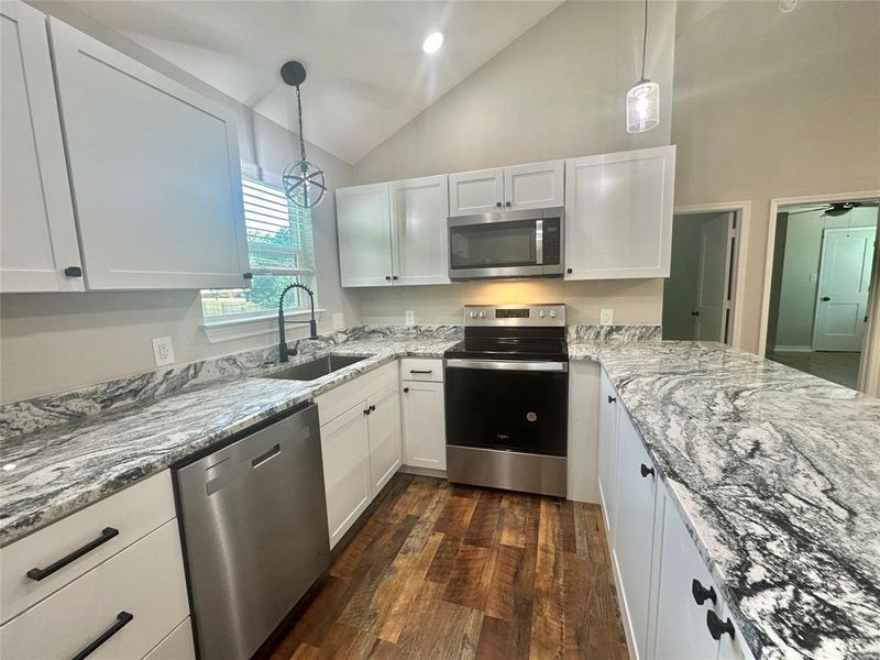 Upstairs Kitchen featuring stainless steel appliances, granite counters, LVP flooring, white cabinets, and hanging light fixtures Upstairs Kitchen featuring stainless steel appliances, granite counters, LVP flooring, white cabinets, and hanging light fixtures