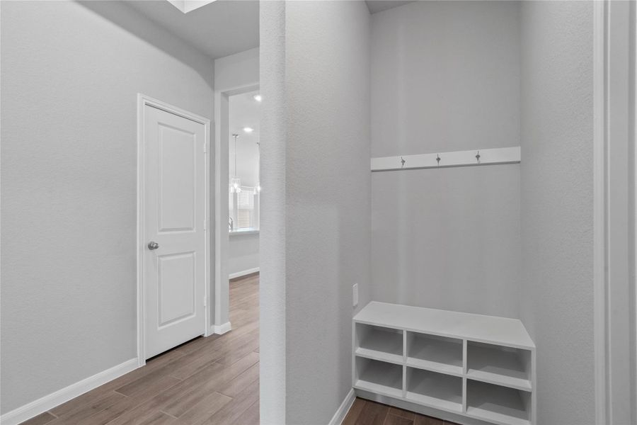 This dedicated area features a custom built-in bench with hooks, perfect for organizing coats, bags, and shoes right off the main hallway, keeping the rest of the home tidy.