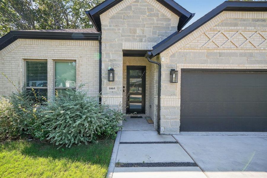 View of front facade featuring an attached garage, stone siding, brick siding, and concrete driveway