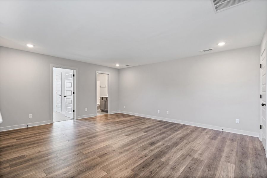 Spacious room featuring wood-finish flooring, recessed lighting, and light gray wall paint