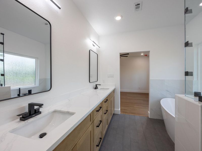 Backlit mirrors, quartz countertops, and modern matte black fixtures complement the custom cabinetry for a sophisticated and functional primary bath. Backlit mirrors, quartz countertops, and modern matte black fixtures complement the custom cabinetry for a sophisticated and functional primary bath.
