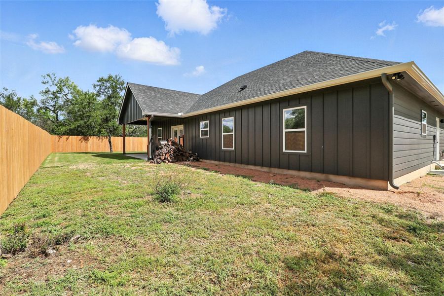 Rear view of house featuring a patio, board and batten siding, a shingled roof, and a fenced backyard