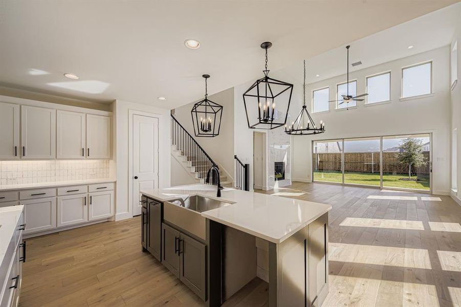 Kitchen featuring light wood finished floors, white cabinets, tasteful backsplash, recessed lighting, and a high ceiling