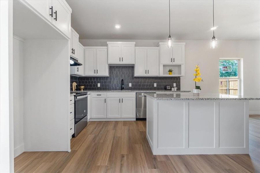 Kitchen with light hardwood / wood-style floors, dishwasher, white cabinets, and stove