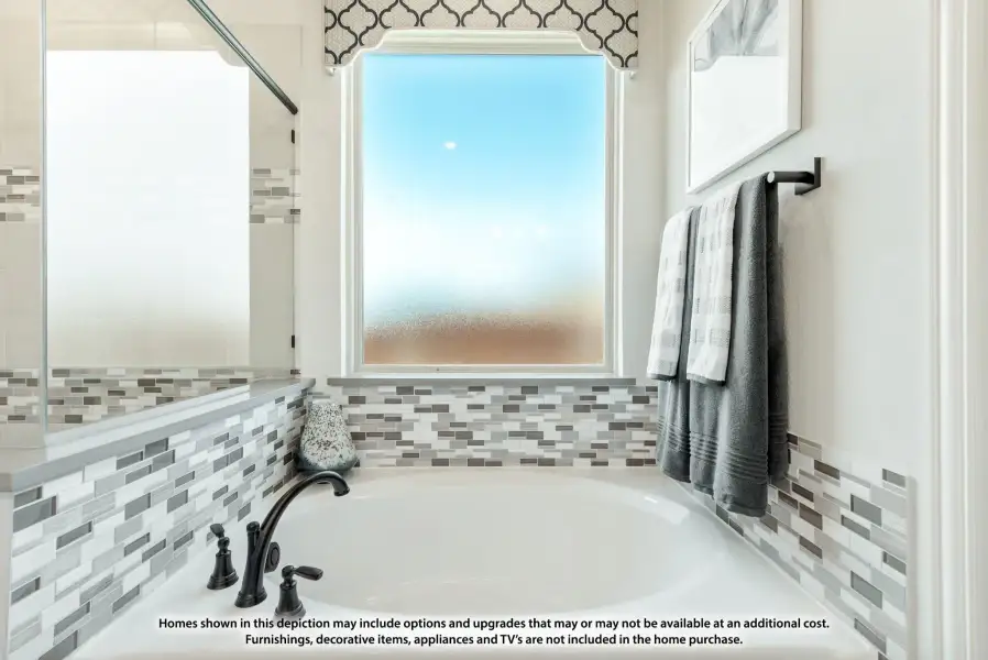 Soaking tub with mosaic tile surround, frosted window, and glass shower enclosure in a master bathroom Soaking tub with mosaic tile surround, frosted window, and glass shower enclosure in a master bathroom