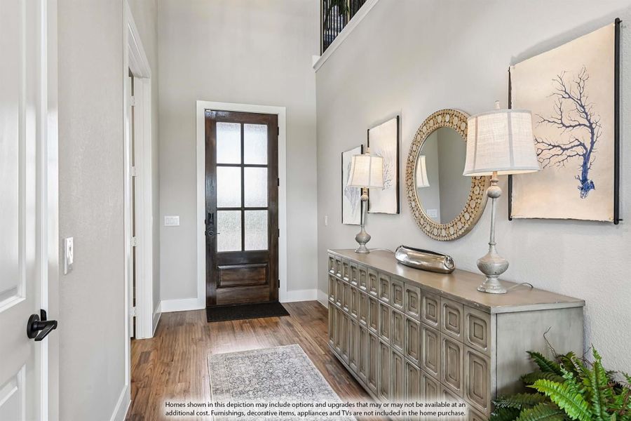 Entryway with dark wood glass-panel front door, hardwood floors, and decorative console table with mirror and lamps Entryway with dark wood glass-panel front door, hardwood floors, and decorative console table with mirror and lamps
